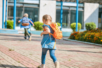 schoolchildren with backpacks run out of school after the end of classes. Classmates, school friends. The beginning of the holidays. End of quarantine. Back to school.