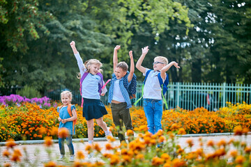 group of schoolchildren with backpacks jump near the school after the end of classes. Classmates, school friends. The beginning of the holidays. End of quarantine. Back to school.