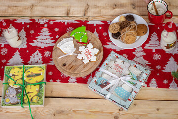 painted Christmas sweets are lying on a textured antique table, tied with a ribbon. gingerbread in glaze with the inscription translates Happy New Year. a bottle of milk.