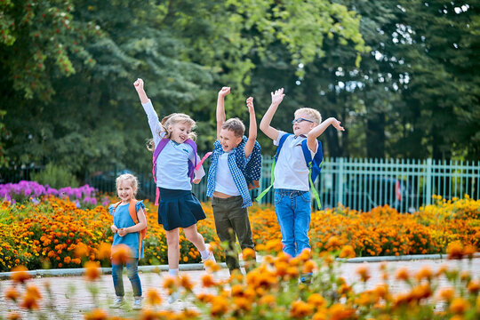group of schoolchildren with backpacks jump near the school after the end of classes. Classmates, school friends. The beginning of the holidays. End of quarantine. Back to school.