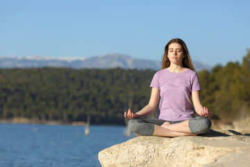 Fototapeta na wymiar Young woman doing yoga in a lake
