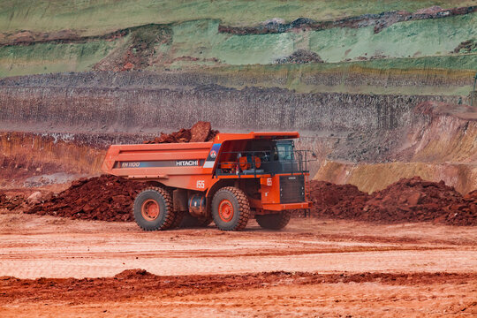 Arkalyk, Kazakhstan - May 15 2012: Aluminium ore mining. Quarry (open-cut) mining. Orange Hitachi dump-truck transporting bauxite clay. Scratches of excavator bucket on background.
