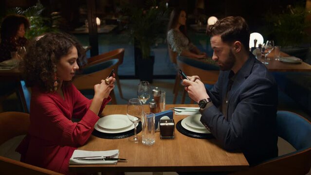Couple ordering food online at fancy restaurant table on romantic evening date. 