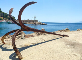 old, rusty anchor on the seashore. at the port with ships and yachts there is an anchor. tourists can see rust at anchor. the anchor lies on the asphalt, left after a boat trip