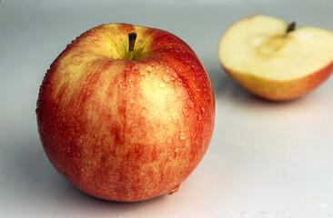 Red apple close-up on a light background. In the background is half an apple, the background is blurred.