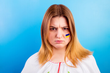 Angry young Ukrainian girl with the flag of Ukraine on her face. The concept of participation of...