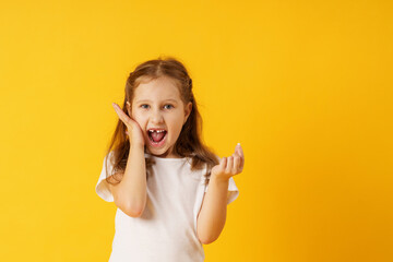 cute smiling preschool girl holds her first fallen baby tooth in her hand while standing on yellow...