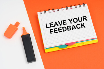 On a white-orange surface lies a marker and a notepad with the inscription - LEAVE YOUR FEEDBACK