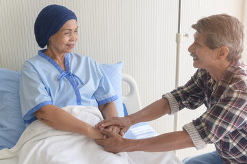Senior man visiting cancer patient woman wearing head scarf at hospital, health care and medical...