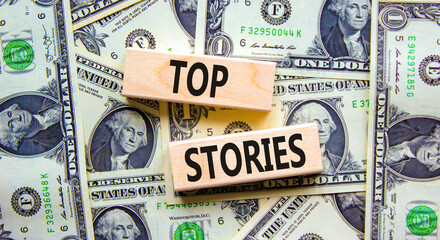 Fototapeta na wymiar Top stories symbol. Concept words Top stories on wooden blocks on a beautiful background from dollar bills. Business story and top stories concept, copy space.