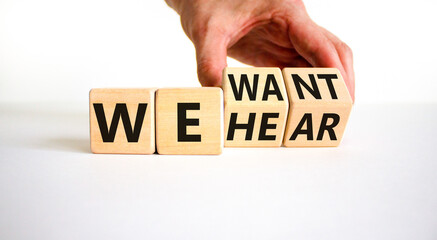 We want and hear you symbol. Businessman turns wooden cubes and changes concept words We hear to We want. Beautiful white table white background. Business we want and hear you concept. Copy space.