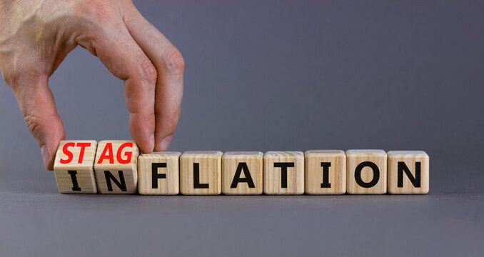 Stagflation or inflation symbol. Businessman turns cubes and changes the concept word inflation to stagflation. Beautiful grey background, copy space. Business stagflation or inflation concept.