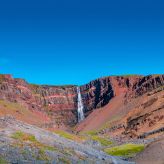 Cover page with beautiful and tall Icelandic waterfall Hengifoss, Iceland, at sunny day and blue sky, summer.