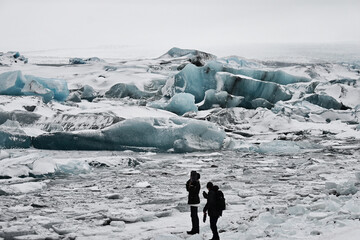 Photographer Silhouettes Standing on Ice Clogged River Bank on Foggy Day in Iceland