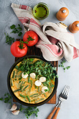 Omelet with spinach, green beans, potato and spinach healthy food in black frying pan on grey stone old rustic background. Traditional frittata for breakfast Eggs tortilla Top view flat lay Copy space