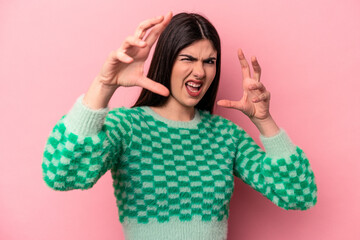 Young caucasian woman isolated on pink background upset screaming with tense hands.