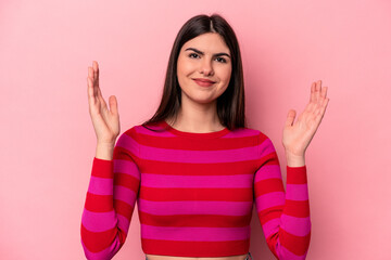 Fototapeta na wymiar Young caucasian woman isolated on pink background holding something little with forefingers, smiling and confident.