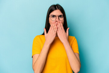 Young caucasian woman isolated on blue background shocked, covering mouth with hands, anxious to discover something new.