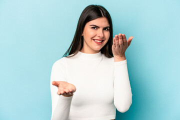 Fototapeta premium Young caucasian woman isolated on blue background makes scale with arms, feels happy and confident.
