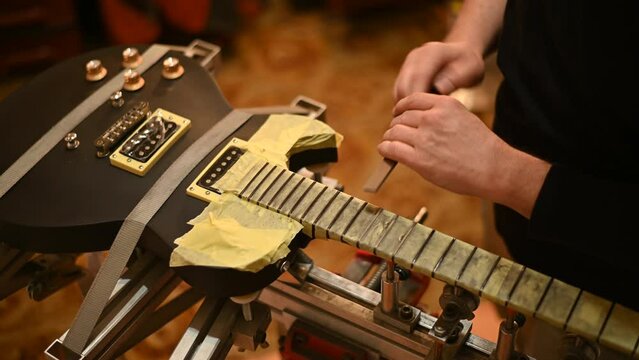 Guitar in repair service shop with a hands of a guitar luthier