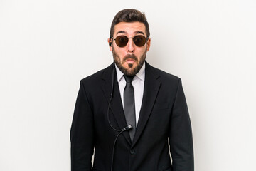 Young caucasian bodyguard man isolated on white background shrugs shoulders and open eyes confused.