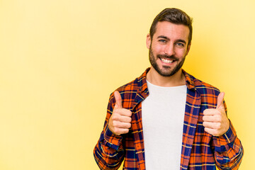 Young caucasian man isolated on yellow background smiling and raising thumb up