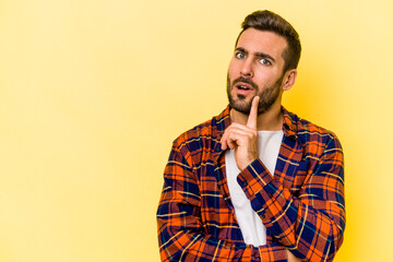 Young caucasian man isolated on yellow background looking sideways with doubtful and skeptical expression.