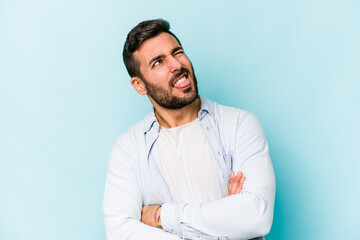 Young caucasian man isolated on blue background funny and friendly sticking out tongue.