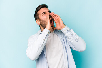 Young caucasian man isolated on blue background shouting excited to front.