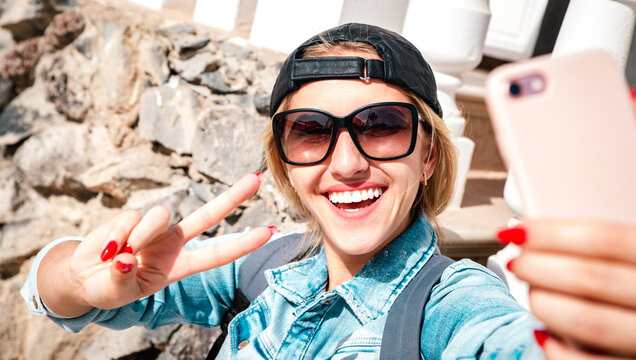 Beautiful woman travel blogger taking selfie at touristic location - Wanderlust vacation and street life style concept with adventure girl wanderer on world tour excursion - Bright vivid filter