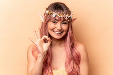 Young elf woman with pink hair isolated on beige background cheerful and confident showing ok gesture.