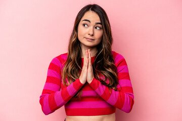 Fototapeta premium Young caucasian woman isolated on pink background praying, showing devotion, religious person looking for divine inspiration.