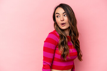 Obraz premium Young caucasian woman isolated on pink background looks aside smiling, cheerful and pleasant.