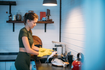 A young woman cleans fish at the sink in the kitchen.