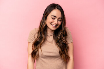 Fototapeta premium Young caucasian woman isolated on pink background laughs and closes eyes, feels relaxed and happy.