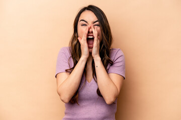 Young caucasian woman isolated on beige background shouting excited to front.