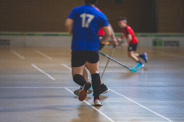 View of floorball match game, court hall indoor venue with junior teenage children school team playing in the background, floor ball hockey match game on arena stadium, copy space