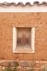 old window with wooden shutters on an adobe brick facade