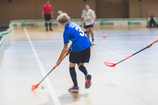 View Of Floorball Match Game, Court Hall Indoor Venue With Junior Teenage Children School Team Playing In The Background, Floor Ball Hockey Match Game On Arena Stadium, Copy Space