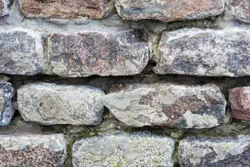 The rough textured surface of the wild stone wall. Background.