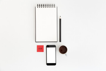 White office table with spiral notebook, pen and mobile screen mock up. Top view