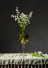 Fotobehang Bouquet of May lilies of the valley in a vase on the table. A dark room © Alexander