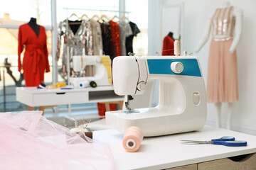 Sewing machine and equipment on table in dressmaking workshop