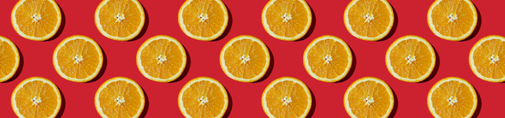 horizontal banner. Summer composition made from oranges, on dark red  background. Creative Pattern made of slices of orange.