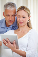 Fototapeta premium Sharing digital freedom with her husband. A married couple sharing a digital tablet at home.