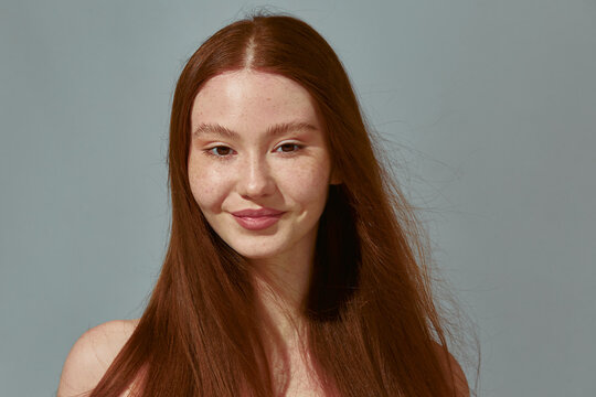 Redhead girl after using fox eye lift tape with bare shoulders, long ginger hair smiling satisfied with foxy eyes effect