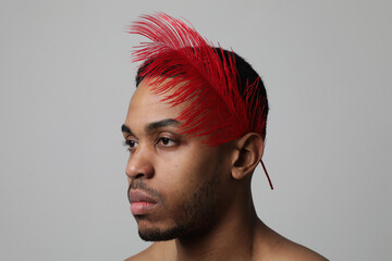 Headshot of young and handsome man with red feather on white background.