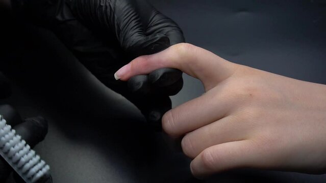 Working on a manicure close-up. Beauty salon hands and nails on a dark background. Video footage