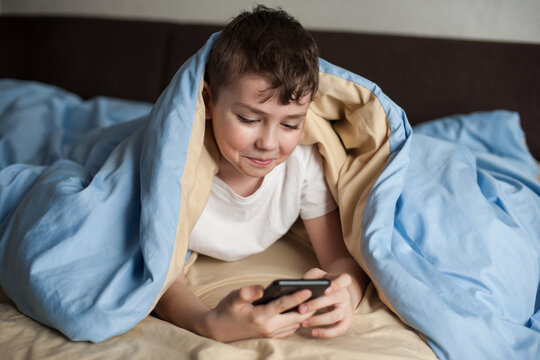 The Boy Lies Under The Covers With The Phone