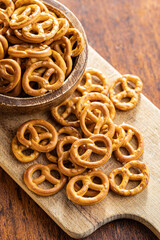 Mini pretzels. Crusty salted snack on cutting board.